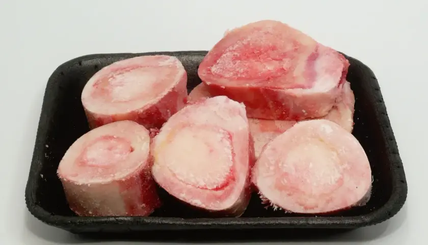 Os à moelle pour chien, crus et congelés, présentés dans un plateau noir. Parfaits pour une alimentation naturelle ou une friandise.